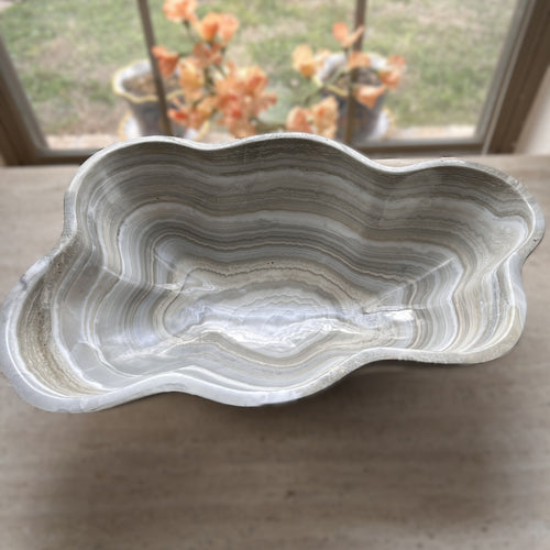 A polished and shine gray onyx stone bowl with natural patterns placed on a flat surface, likely used as a decorative centerpiece.