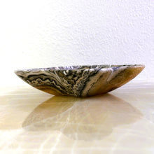 Load image into Gallery viewer, An elegant hand-carved stone bowl with capricious veins in beige and light brown tones, placed on a marble surface.
